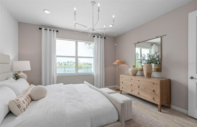 bedroom featuring light wood-style floors, baseboards, and a notable chandelier