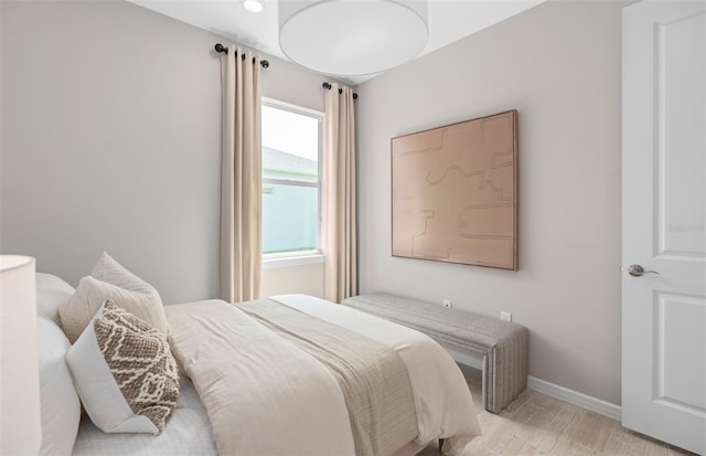 bedroom with light wood finished floors and baseboards