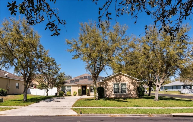 view of front of house with a front lawn, fence, driveway, and roof mounted solar panels