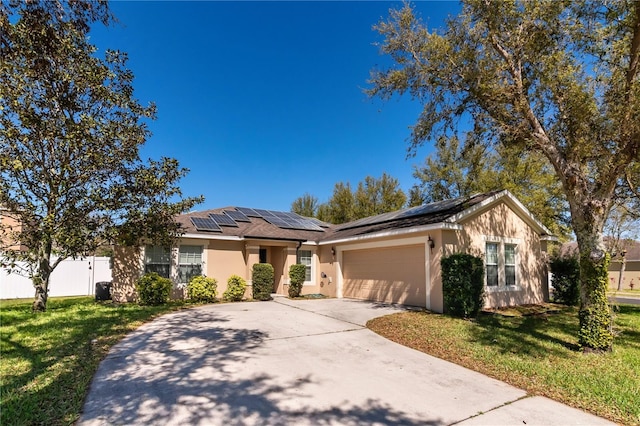 ranch-style house featuring a front lawn, fence, concrete driveway, a garage, and solar panels