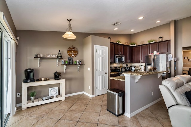 kitchen featuring a breakfast bar, light stone counters, open floor plan, stainless steel appliances, and dark brown cabinets