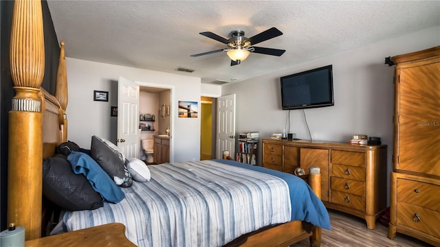 bedroom with visible vents, connected bathroom, a textured ceiling, and wood finished floors