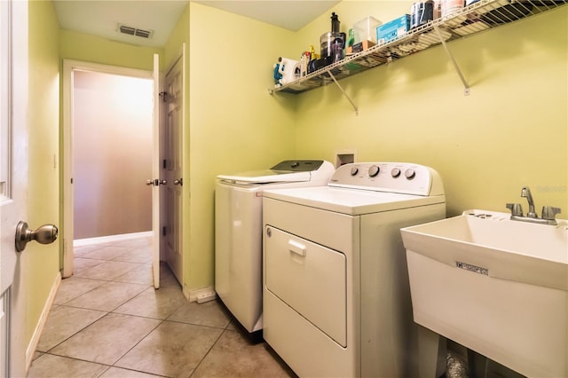 laundry room with visible vents, washer and clothes dryer, light tile patterned floors, laundry area, and a sink