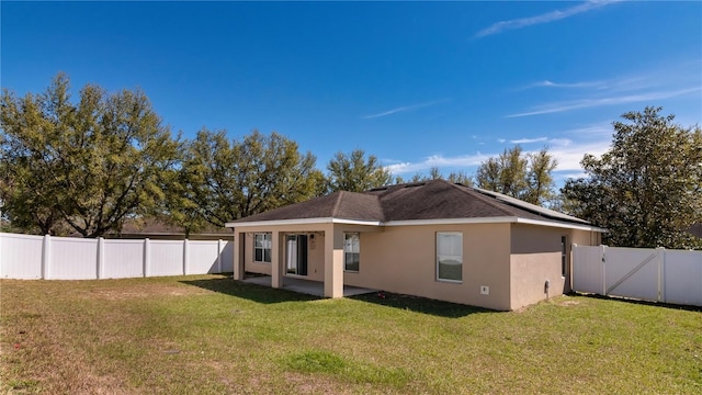 back of property featuring a patio, solar panels, a yard, a fenced backyard, and stucco siding