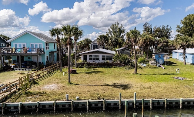 rear view of house featuring fence, a lawn, and a deck with water view