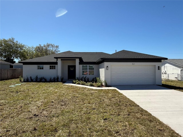 view of front facade with stucco siding, fence, a garage, driveway, and a front lawn