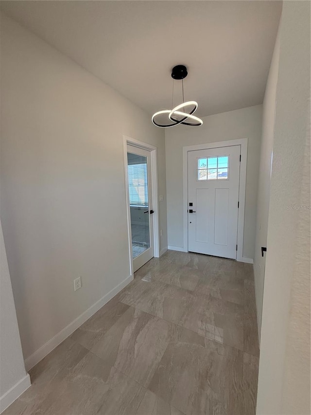 foyer with baseboards and a chandelier