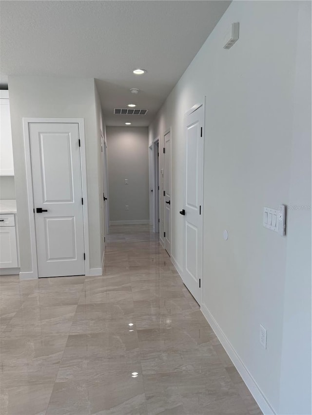 hall with marble finish floor, baseboards, and visible vents