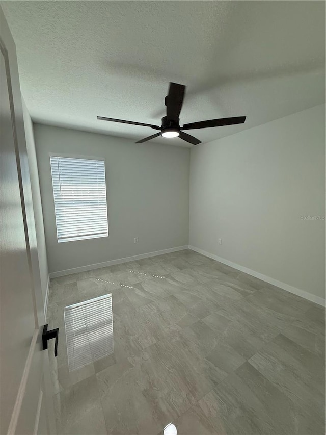 spare room featuring a ceiling fan, baseboards, and a textured ceiling