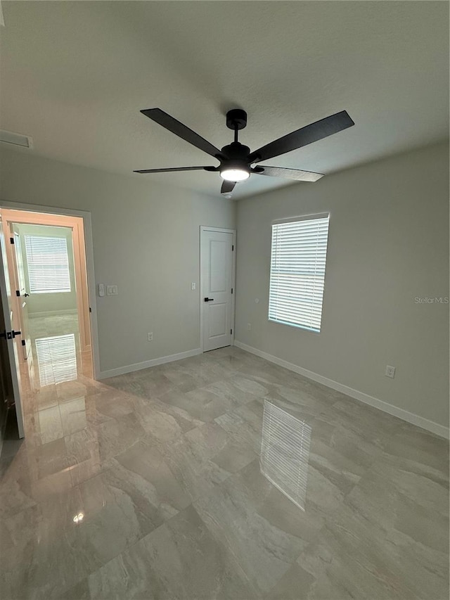 spare room featuring visible vents, ceiling fan, and baseboards