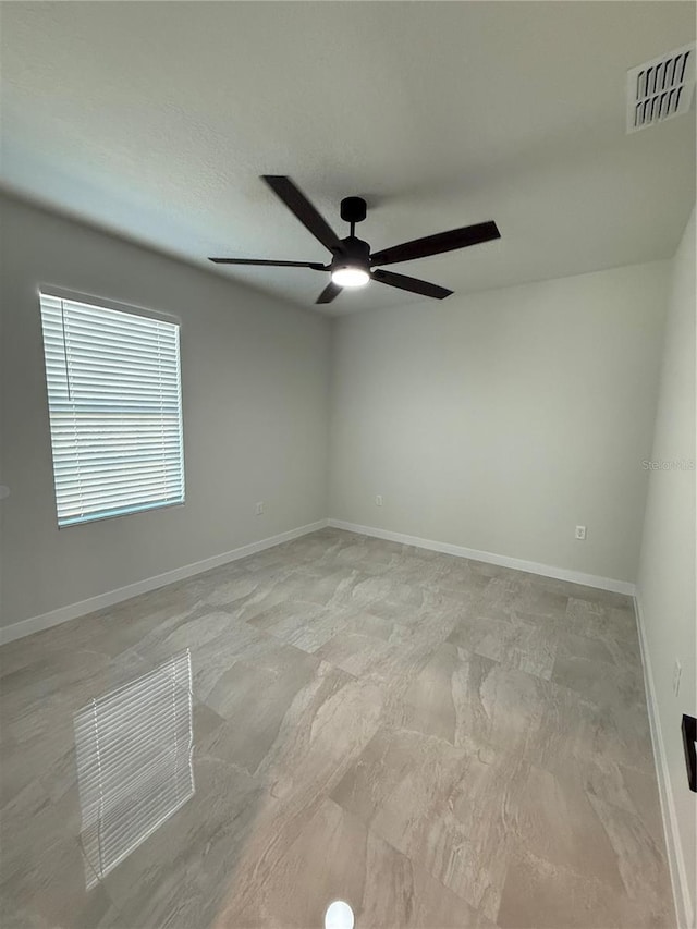 empty room with visible vents, ceiling fan, and baseboards