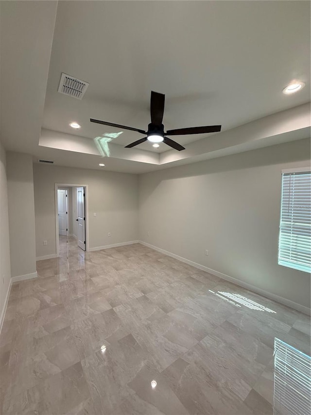 unfurnished room featuring a tray ceiling, visible vents, and baseboards