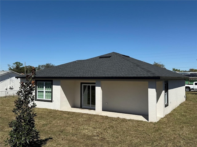 back of property with roof with shingles, a yard, and stucco siding