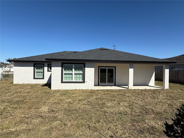 back of property featuring a shingled roof, fence, a yard, stucco siding, and a patio area