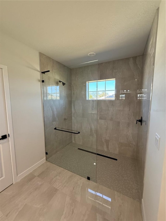 bathroom with a textured ceiling, baseboards, and a walk in shower