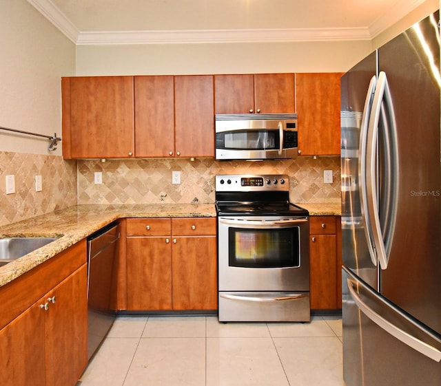 kitchen with appliances with stainless steel finishes, brown cabinetry, light tile patterned flooring, and crown molding