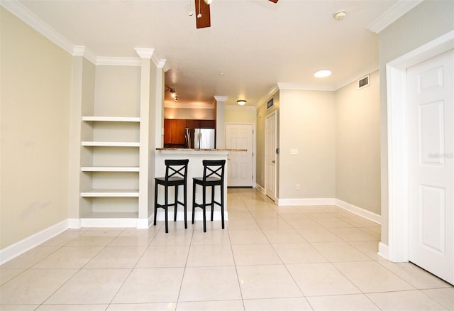 kitchen with built in shelves, ornamental molding, a kitchen breakfast bar, and freestanding refrigerator