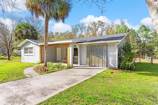 view of front of property featuring concrete driveway, a front yard, fence, and stucco siding