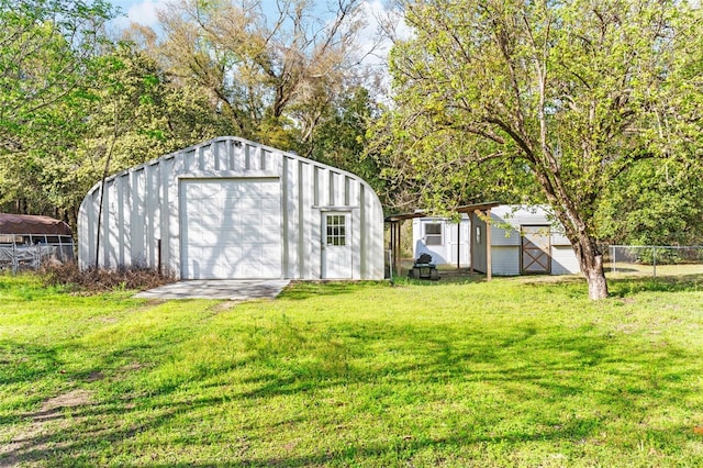 view of outdoor structure with an outbuilding, fence, and driveway