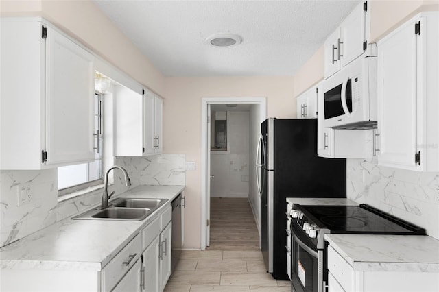 kitchen with stainless steel appliances, a sink, light countertops, and white cabinetry