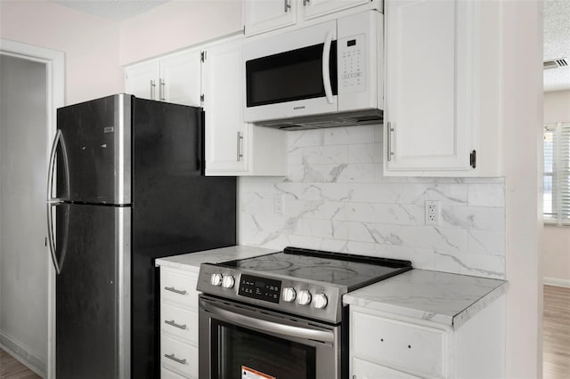 kitchen featuring white cabinetry, appliances with stainless steel finishes, decorative backsplash, and wood finished floors