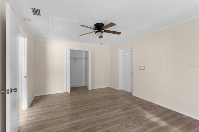 unfurnished bedroom with visible vents, a textured ceiling, baseboards, and wood finished floors
