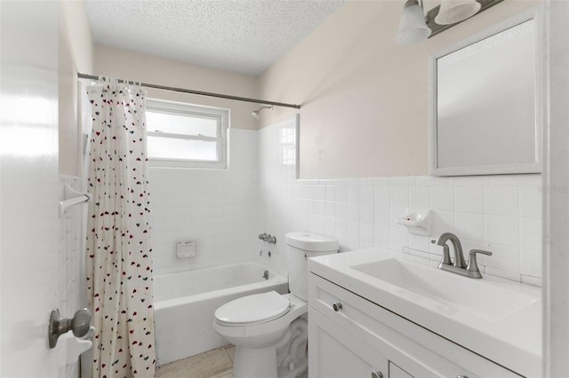 full bathroom featuring toilet, a wainscoted wall, shower / bath combination with curtain, a textured ceiling, and tile walls