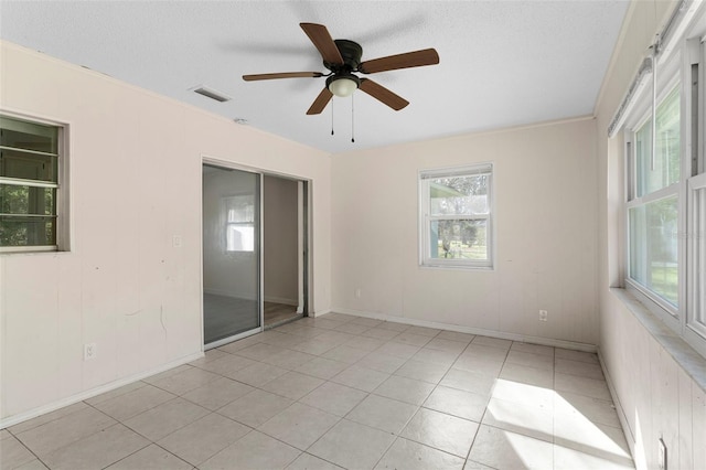 spare room with light tile patterned floors, visible vents, ceiling fan, a textured ceiling, and baseboards