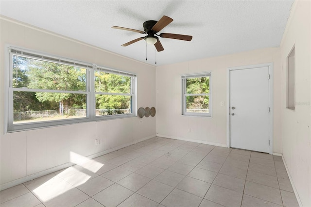 spare room with light tile patterned floors, baseboards, a ceiling fan, and a textured ceiling