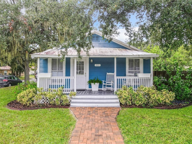 bungalow-style house with a porch, metal roof, and a front lawn