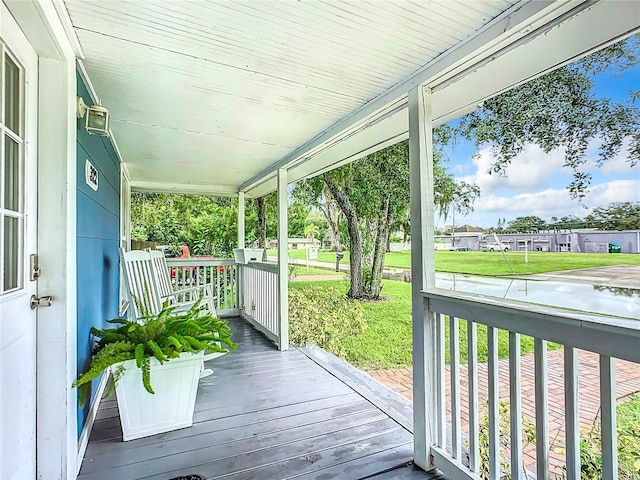 deck with a residential view, covered porch, and a yard