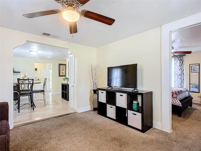 carpeted living area featuring ceiling fan, visible vents, and baseboards