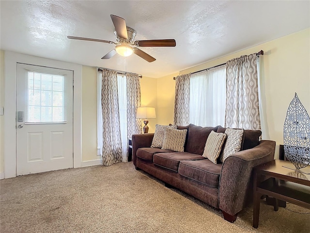 living area featuring carpet floors, ceiling fan, and a textured ceiling