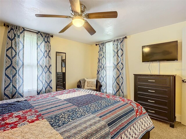 bedroom featuring ceiling fan, multiple windows, and light colored carpet