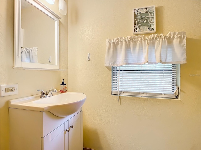 bathroom with a textured wall and vanity