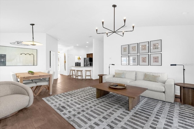 living area featuring a chandelier, vaulted ceiling, and wood finished floors