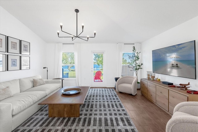 living area featuring vaulted ceiling, an inviting chandelier, wood finished floors, and a healthy amount of sunlight