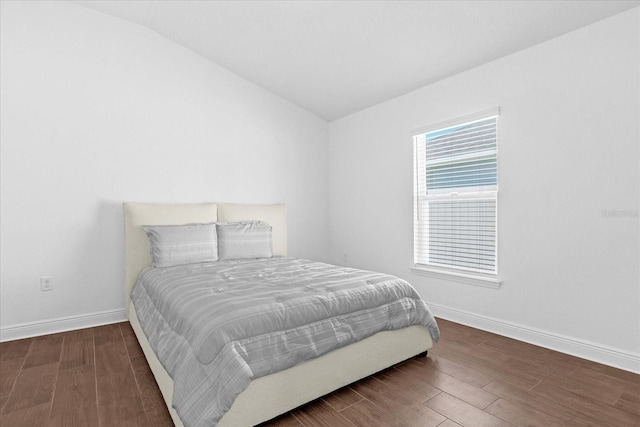 bedroom featuring lofted ceiling, baseboards, and wood finished floors