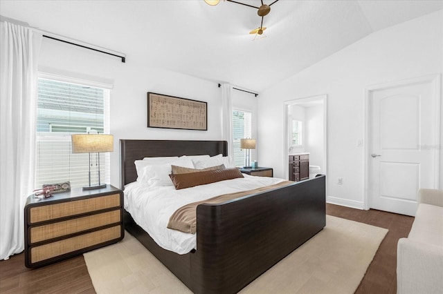 bedroom with lofted ceiling, multiple windows, dark wood-style floors, and ensuite bathroom