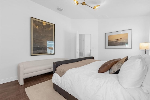 bedroom with baseboards, visible vents, and wood finished floors