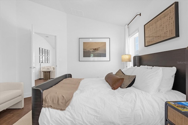 bedroom featuring lofted ceiling, visible vents, and wood finished floors