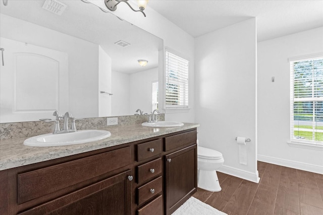 full bath with toilet, a wealth of natural light, and a sink