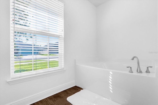 bathroom featuring baseboards, a bath, and wood finished floors