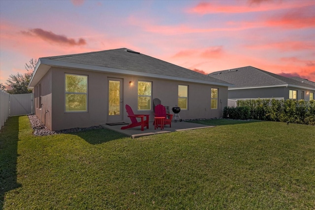 rear view of property with a patio area, a fenced backyard, a yard, and stucco siding