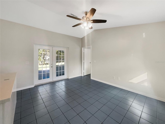 empty room featuring baseboards, a ceiling fan, vaulted ceiling, french doors, and dark tile patterned floors