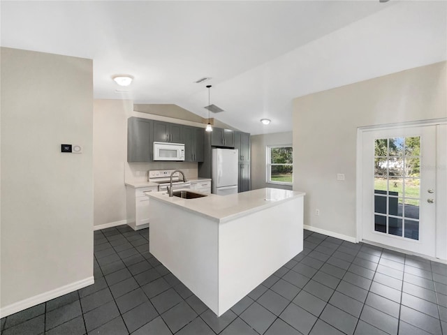 kitchen featuring white appliances, dark tile patterned floors, a sink, vaulted ceiling, and light countertops