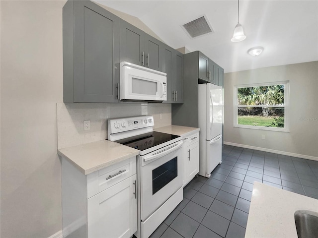 kitchen featuring light countertops, visible vents, white appliances, dark tile patterned floors, and baseboards