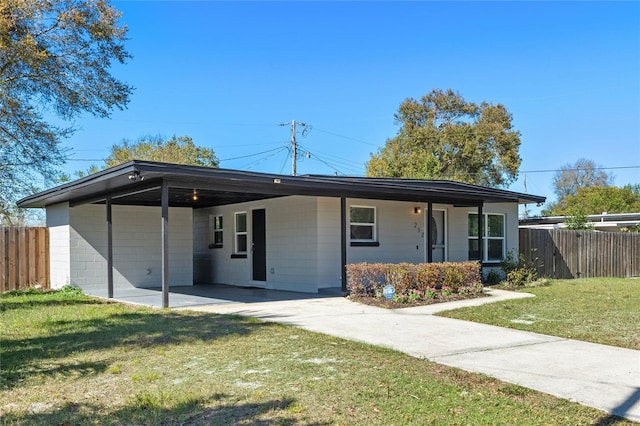 view of front of home with driveway, a front lawn, concrete block siding, and fence