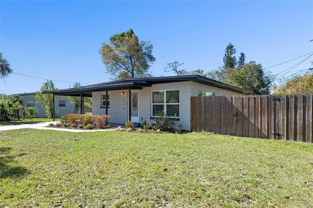 view of front of home with a carport, a front yard, and fence