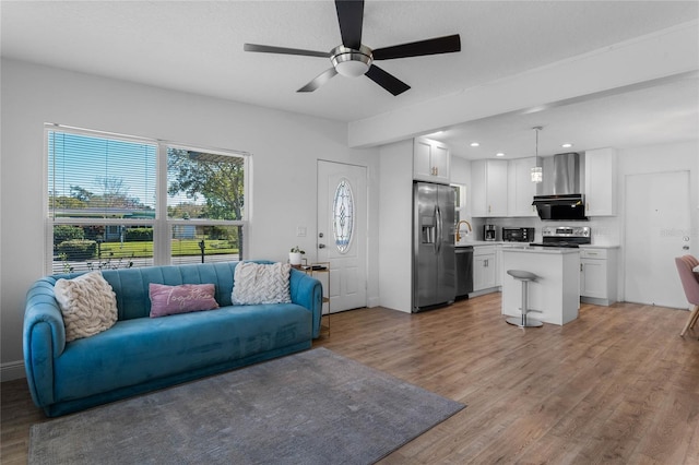 living room with light wood-style floors, a ceiling fan, and recessed lighting